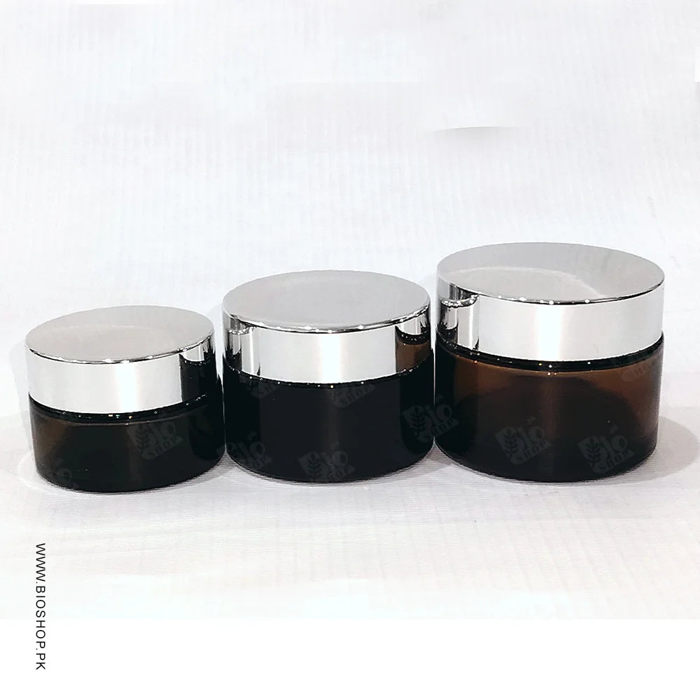Three black cosmetic jars with silver lids on a white background
