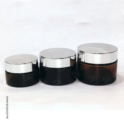 Three black cosmetic jars with silver lids on a white background
