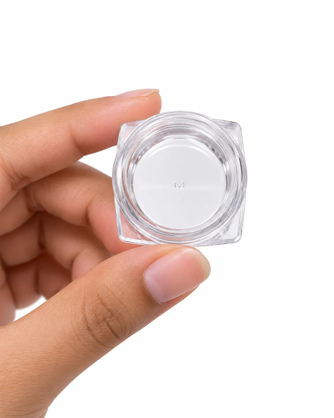 Hand holding a 5gm clear square cosmetic sample jar with a glossy orange lid